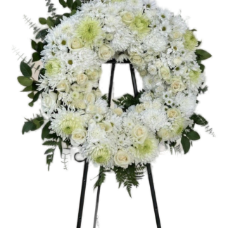 White standing sympathy wreath with roses, chrysanthemums, and eucalyptus on an easel stand