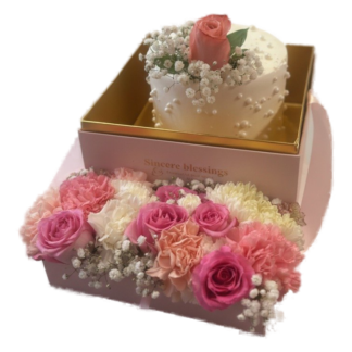 Mini cake topped with a rosebud inside a pink rose and carnation flower box