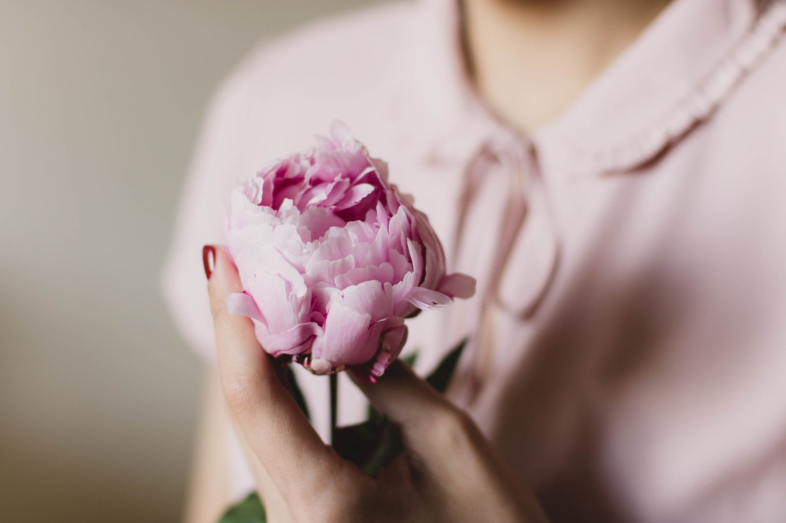 Woman holding a pink peony flower